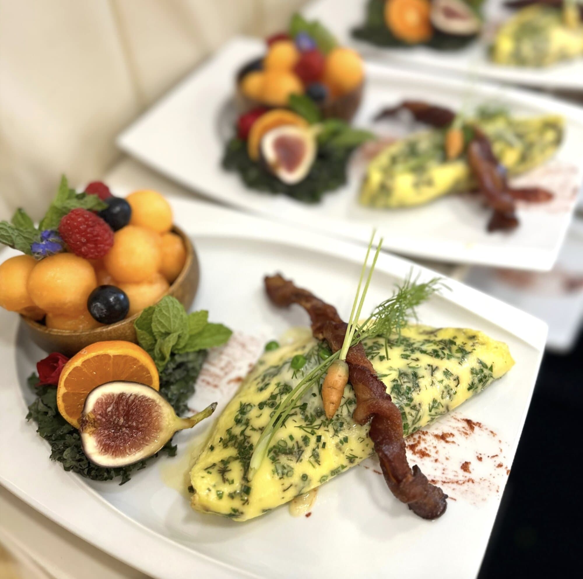 Herbed omelette plated with figs and melon balls